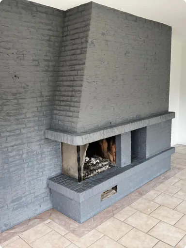 Kamin mit grau gestrichener Klinkerwand